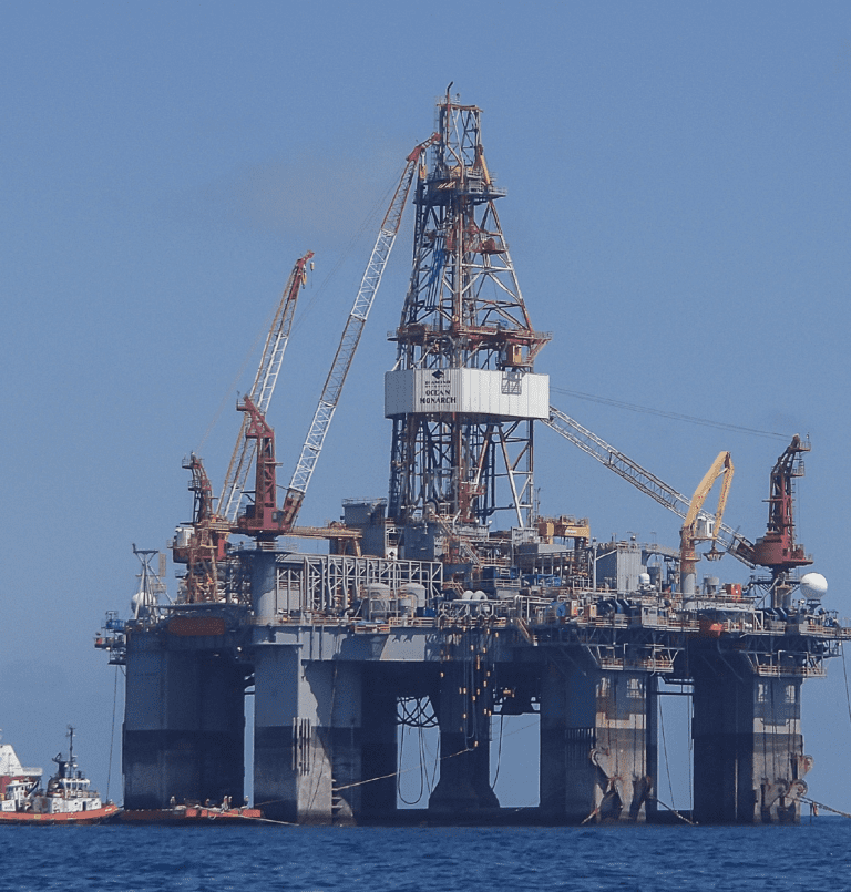A large offshore oil rig with cranes above the water surface.