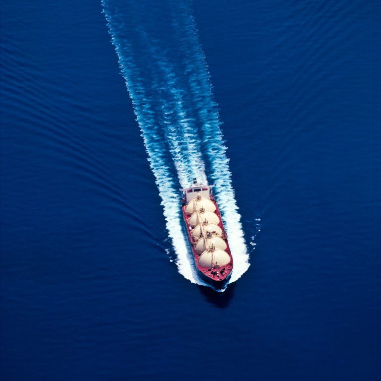 Aerial view of a ship creating a wake in deep blue water.
