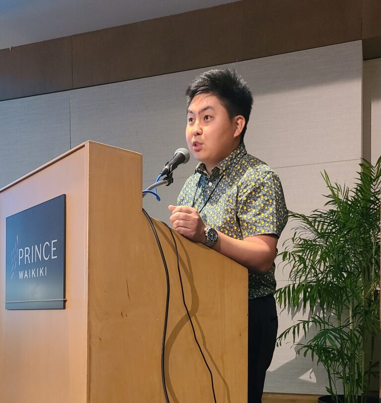 Man speaking at a podium during a presentation.