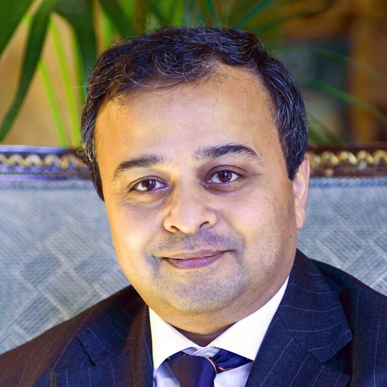 Professional man in suit smiling in an indoor setting.