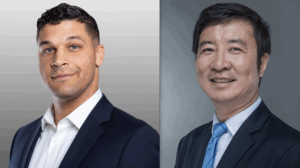 Two men in business suits smiling.