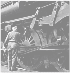 Worker inspecting steam locomotive drive wheels